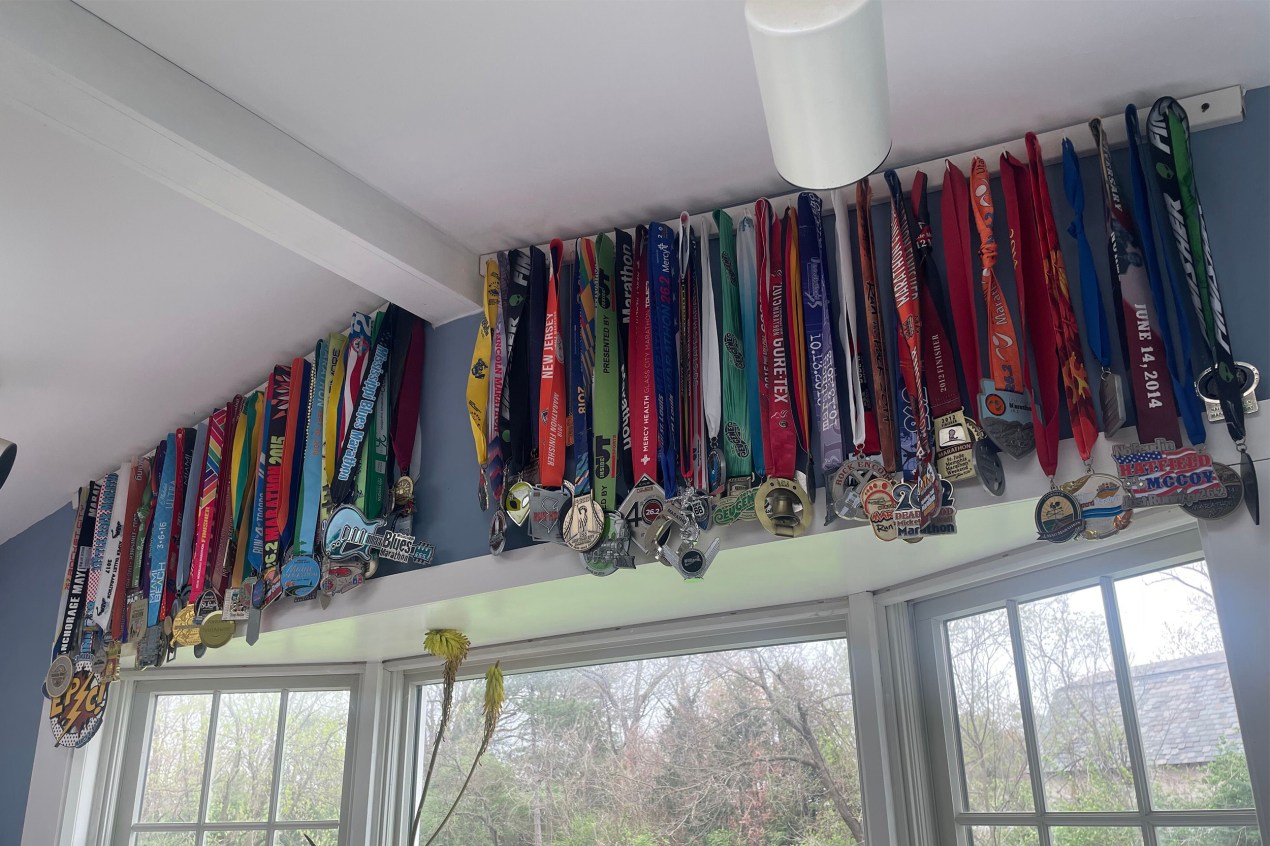 At least 50 medalls attached to ribbons hang from hooks mounted above a picture window.