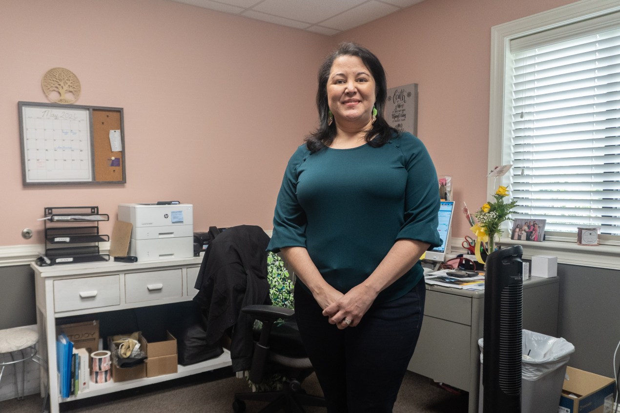 A photo of a woman standing in her office.